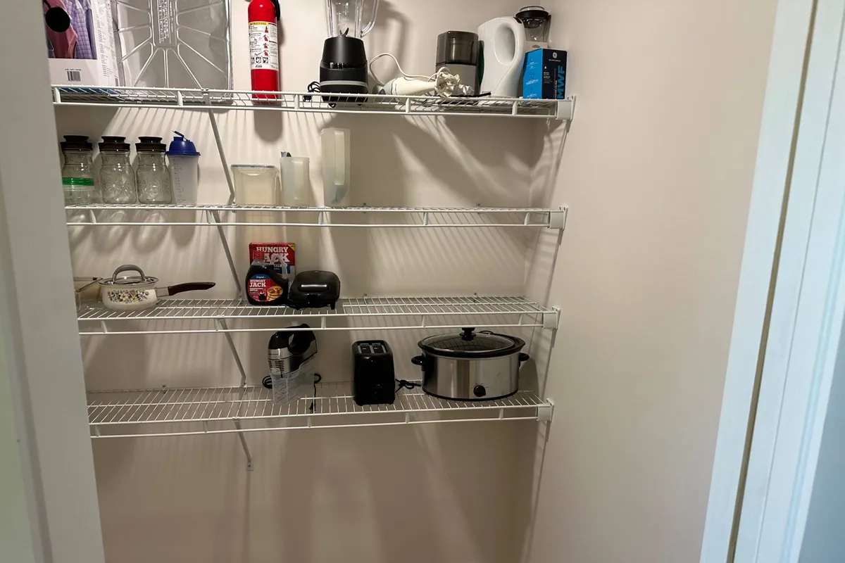 A close-up view of organized kitchen shelving and modern appliances. Glass jars and shelves offer storage inspiration, while the appliances hint at the kitchen’s readiness for meal prep and family gatherings. The layout emphasizes practicality and storage—a must for extended stays and active lifestyles.
