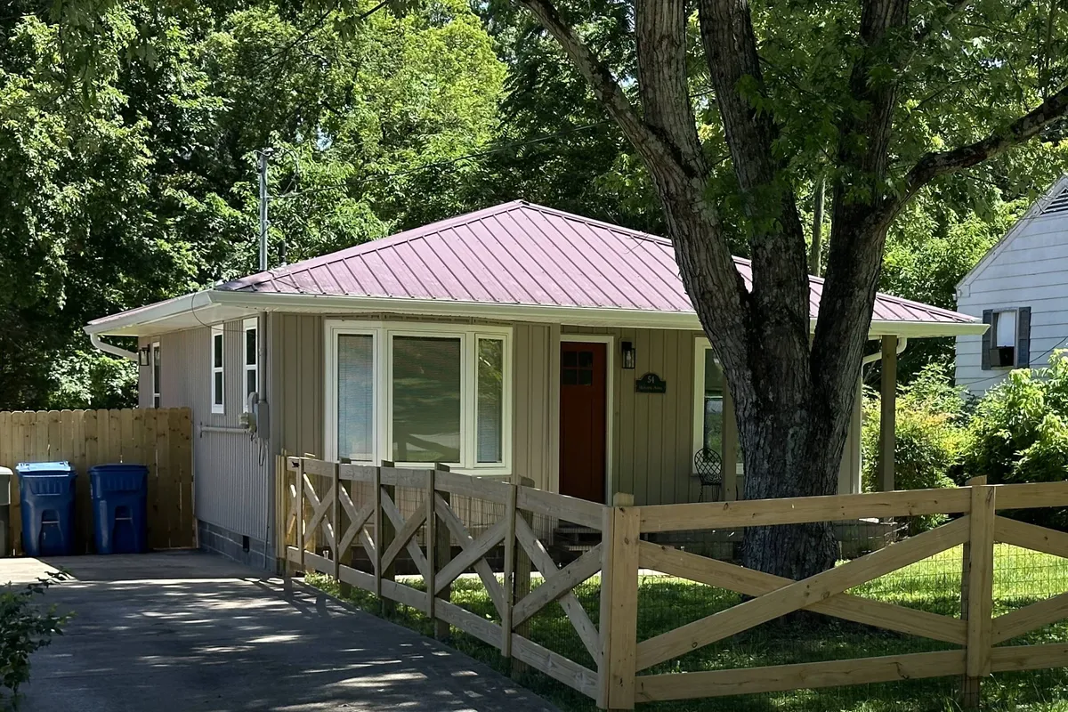 The hero image showcases a charming, fully remodeled bungalow set amidst a lush yard, with a welcoming front porch, a mature shade tree, and a classic white fence, creating an inviting and homey atmosphere ideal for relaxing and gathering outdoors.